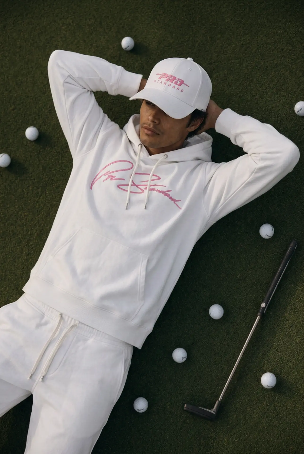 Model in the white signature hoodie lying on the putting green