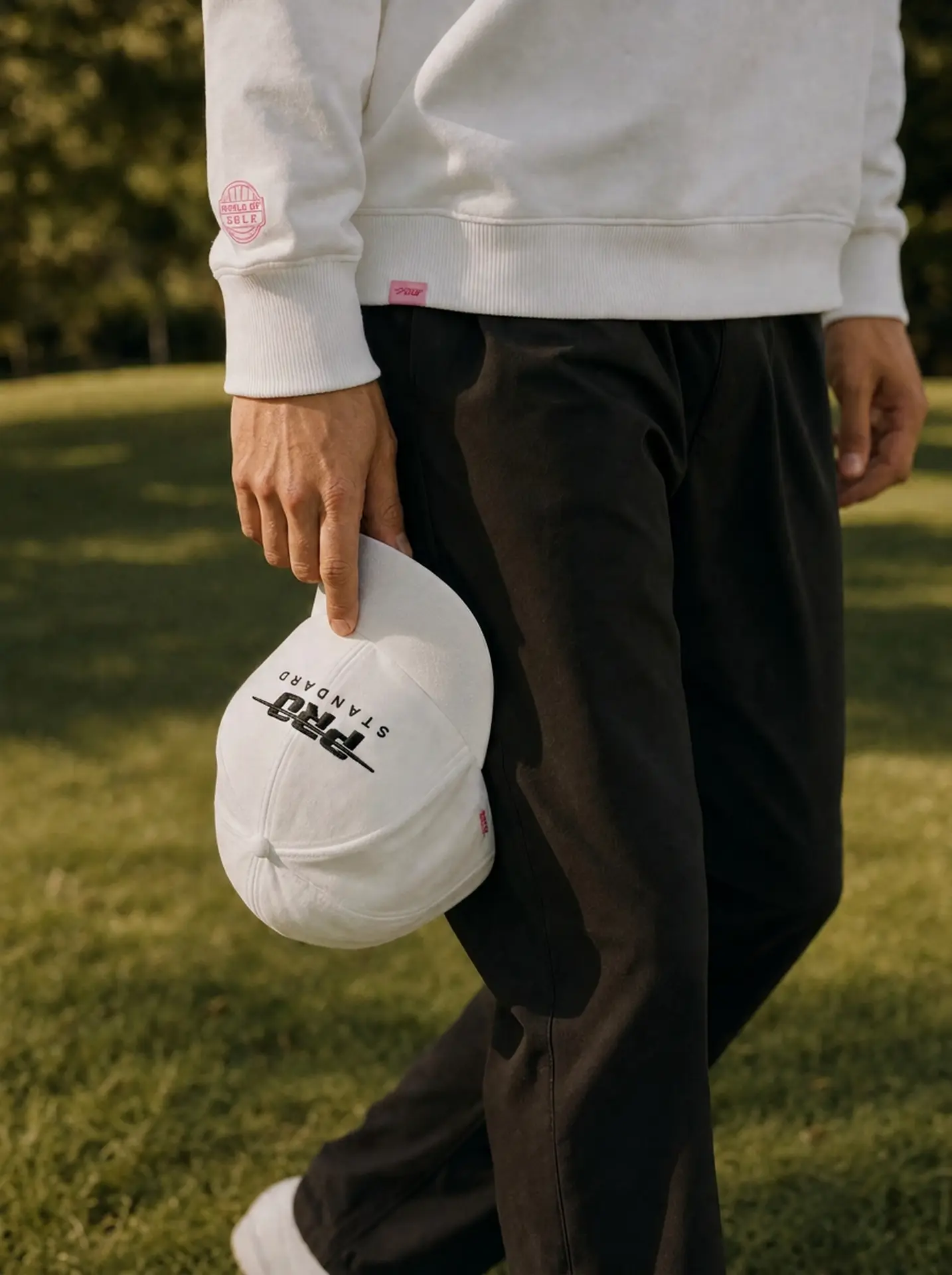Close-up of a hand holding a white Pro Standard cap